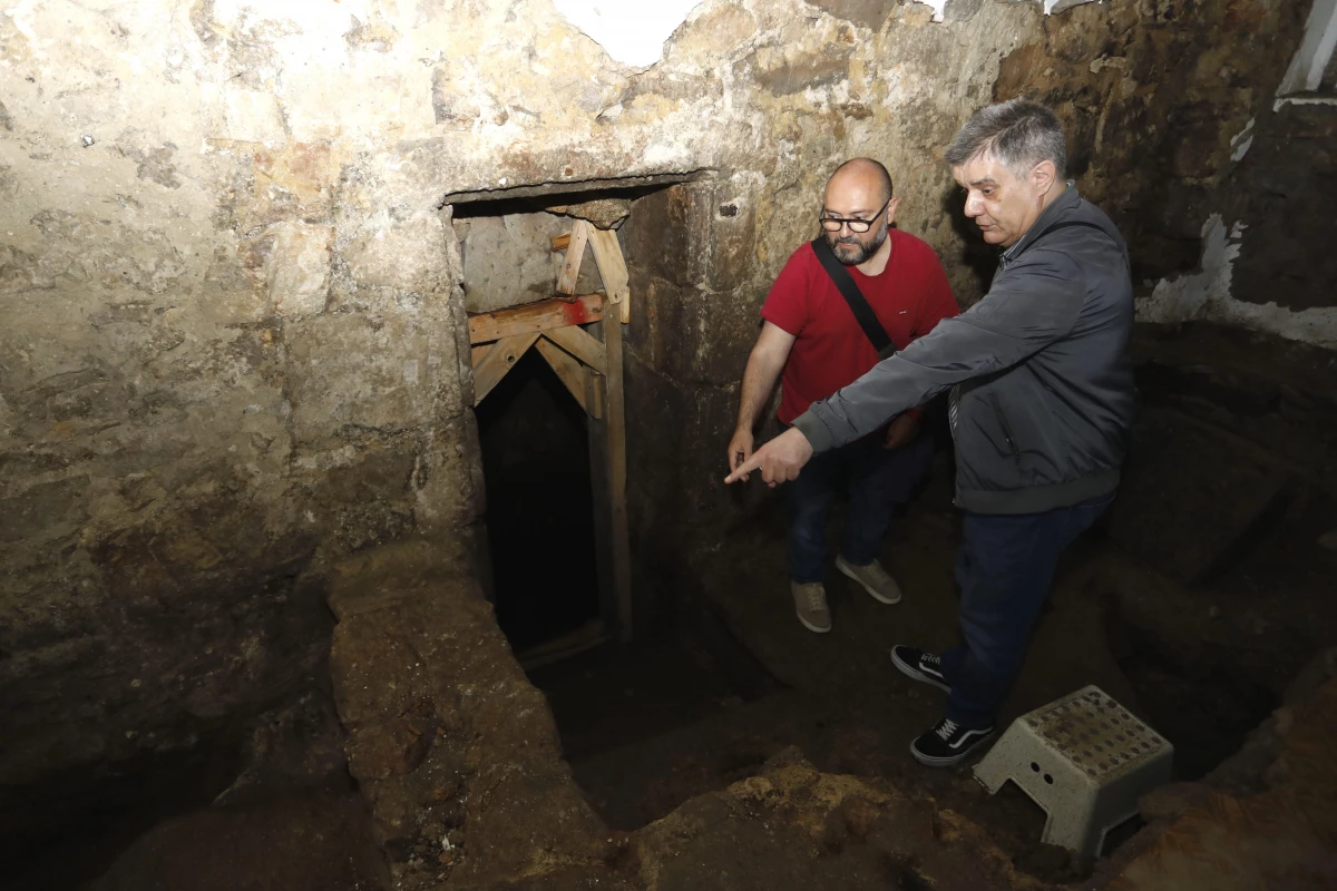 El arqueólogo municipal Marco Antonio Rivas y el investigador Xosé Crisanto Gándara señalan, frente a la puerta de entrada al baño judío, el punto en el que fue encontrada una espina de bacalao | Patricia G. Fraga